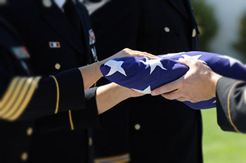 Close up of hands passing a folded flag to another set of hands