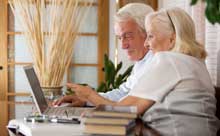 Photo of an elderly man and woman working on a computer. 